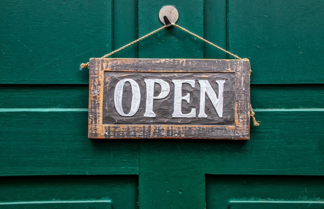 A rustic wooden 'Open' sign on a green wooden door